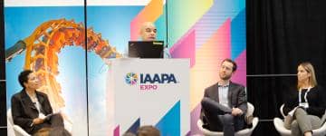 Three seated panelists listen to one speaker on stage.